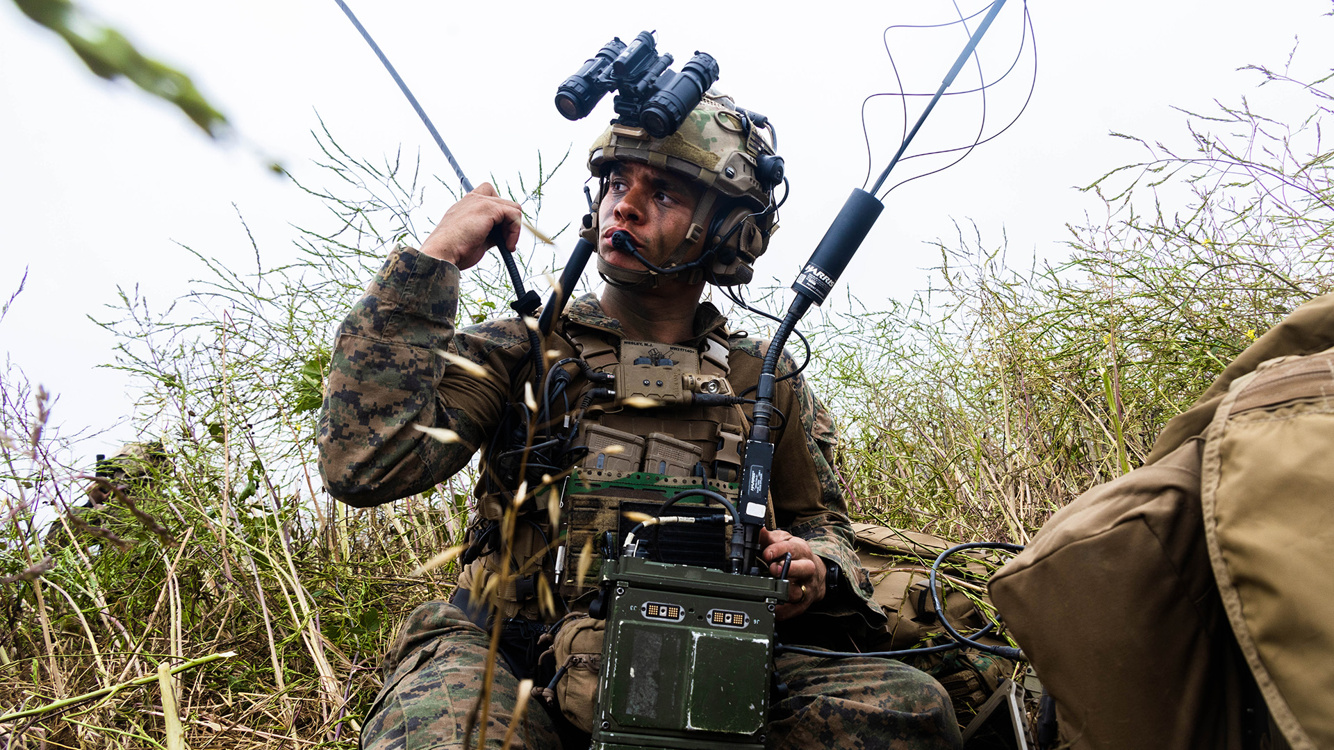 A Marine uses communications equipment in a field. 